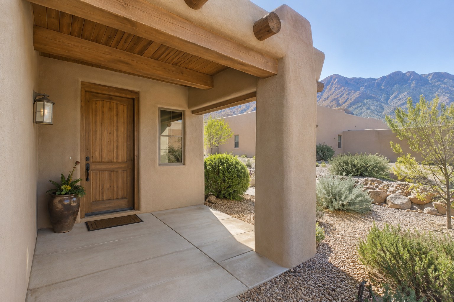A covered front entry of an adobe style home, illustrative